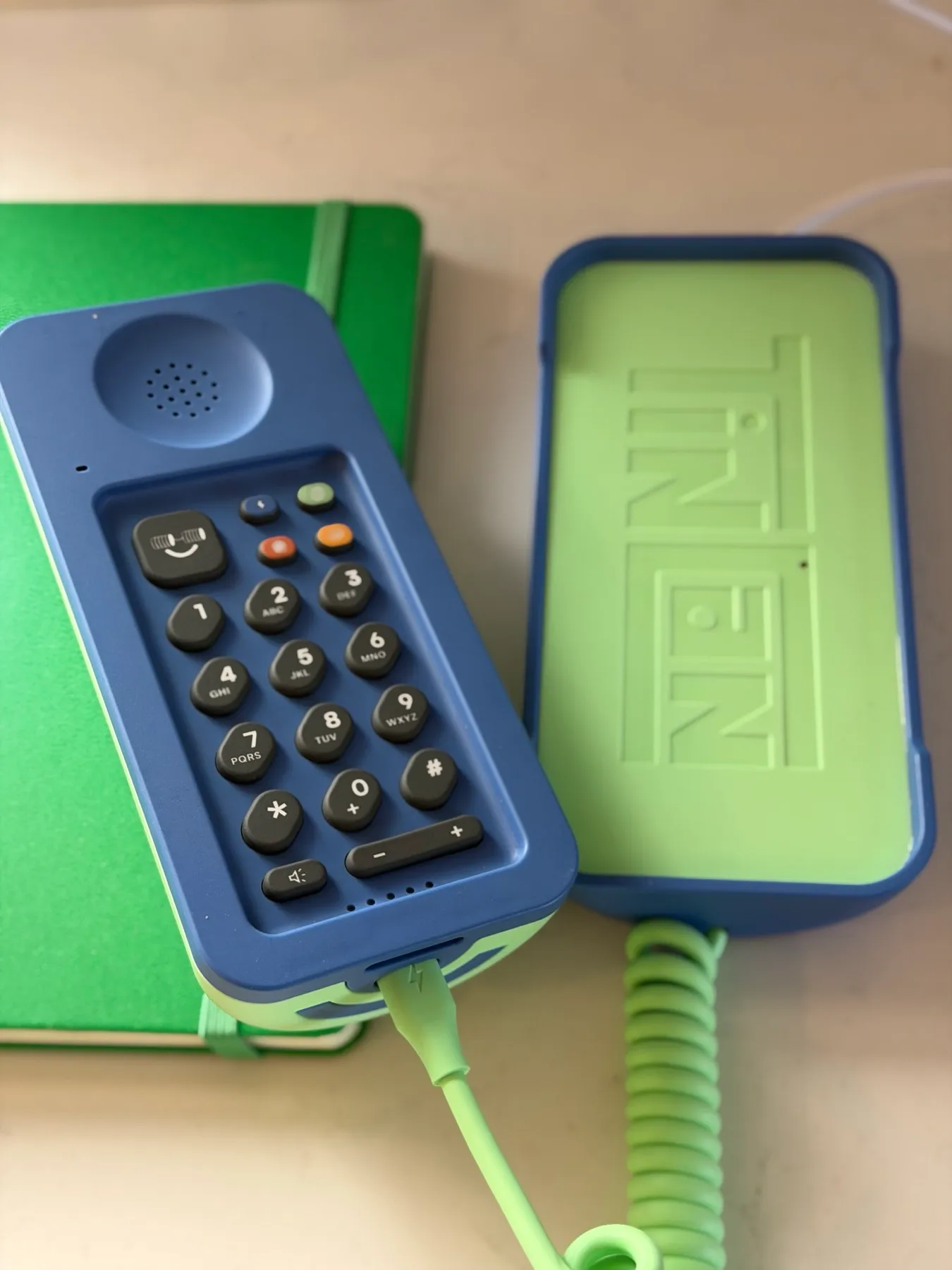 The Tin Can keypad with its voicemail button, next to the open cradle with the embossed logo and charging cable