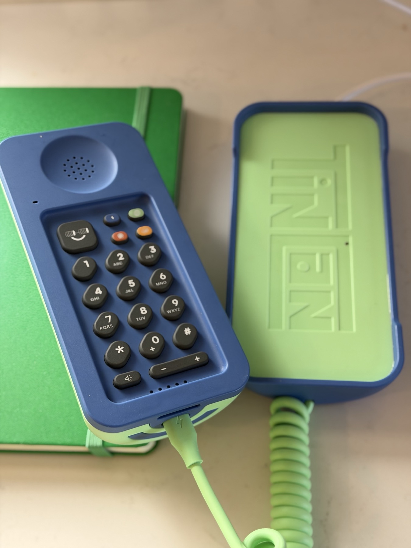 The Tin Can keypad with its voicemail button, next to the open cradle with the embossed logo and charging cable
